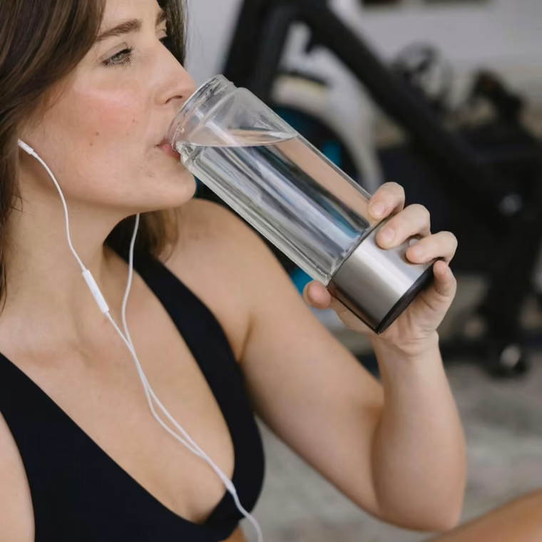 Femme buvant de l'eau hydrogénée Aquivor pendant sa séance de sport
